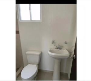 Un baño blanco con inodoro y lavabo. en Habitación para descansar, en Tijuana