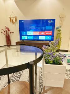 een woonkamer met een glazen tafel en een televisie bij Boulevard Apartment-H1 in Riyad