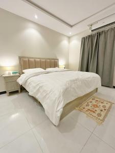 een witte slaapkamer met een groot bed en een raam bij Boulevard Apartment-H1 in Riyad +8 foto's