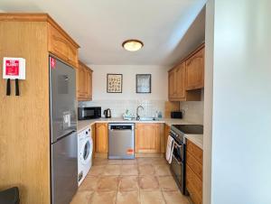 a kitchen with wooden cabinets and a stainless steel refrigerator at Oceanfront Gem Overlooking Cobh in Cobh