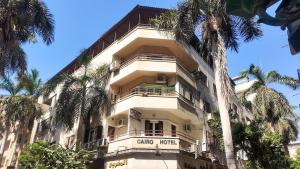 a white building with palm trees in front of it at Khan Al-Andalus in Cairo
