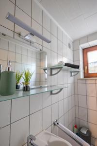 a white tiled bathroom with a sink and shelves at HANNIBAL - Studio-Apartment Iris 10, Parkplatz, Küche, WLAN, Nähe Autobahn in Wolfsburg +37 photos