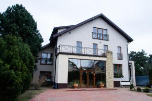 a white house with glass doors and windows at Po Jūros Banga in Palanga