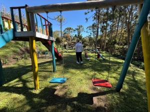 a person standing next to a swing in a playground at Chalé 01 maritacas in Cunha