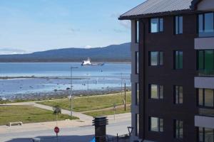 un avión volando sobre el agua cerca de un edificio en Departamentos Natales, en Puerto Natales