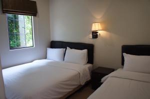 una camera con due letti con lenzuola bianche e una finestra di Hotel Hong a Malacca