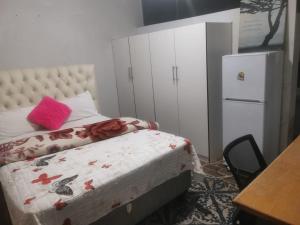 a bedroom with a bed with a pink pillow on it at Tenders Accommodation Rooms Mafikeng in Mahikeng