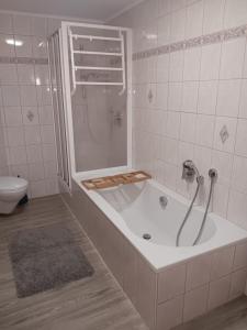 a bathroom with a tub with a shower and a toilet at Ferienwohnung Butterfly in Lam +18 photos