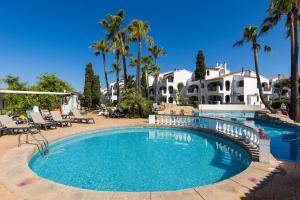 a swimming pool in front of a house with palm trees at Binilivin' Menorca CalaPorter in Cala en Porter