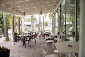 ein Restaurant mit Tischen, Stühlen und Fenstern in der Unterkunft Hotel Saturday in Palma Campania