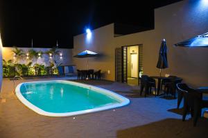 a swimming pool with a table and chairs and an umbrella at Flat Bélgica Piscina e Conforto in Olímpia