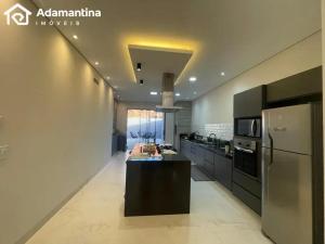 a large kitchen with a refrigerator and a counter at Casa Premium Adamantina in Adamantina