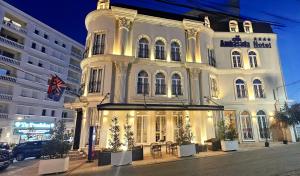 a large white building with tables in front of it at Hotel Ambasada QTA in Patza-Kuqani