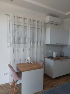 a kitchen with white cabinets and a table with chairs at Apartmani Halilčević in Dubrave Gornje