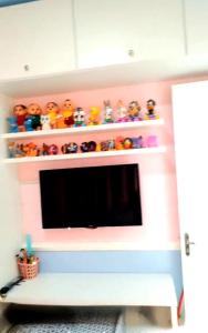 a living room with a tv and shelves with toys at Casa Ananin in Ananindeua