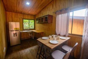 a kitchen with a table with chairs and a refrigerator at La jungla ecolodge in San Juan