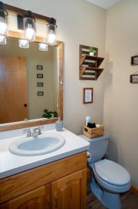 a bathroom with a sink and a toilet and a mirror at Serenity Falls - Stylish 4Bdr Mountain Retreat, Hot Tub, Pool in East Stroudsburg
