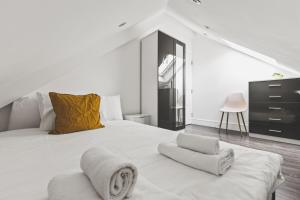 a white bedroom with a large bed with towels on it at Modern 2bed flat near station - COU B in Coulsdon