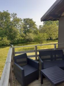 two chairs and a table on a deck with a field at Chalet a la montagne in Cornod