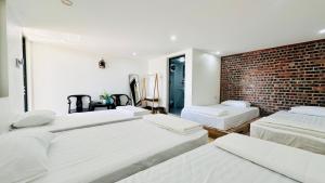 a bedroom with three beds and a brick wall at Queen House in Hoàng Ngà