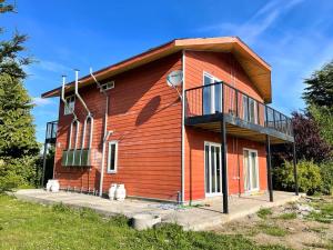un edificio in legno con balcone sul lato di ApartHotel Cuatro Estaciones Frutillar Bajo a Frutillar