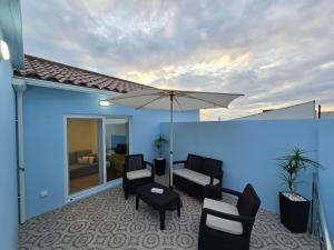 un patio con sedie e un ombrellone su un edificio blu di Brisa do Mar Azorean House a Maia