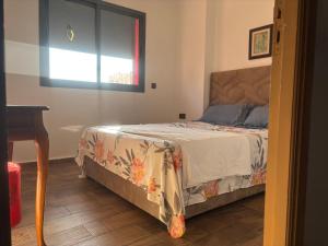 a bedroom with a bed and a table and a window at Cozy apartment near the airport in Deroua +3 photos