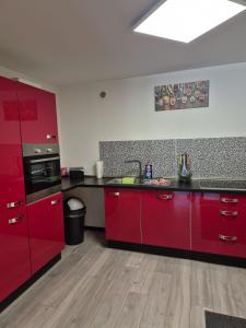 a kitchen with red cabinets and a black counter top at Ferienwohnung Waldblick 2 für 4 Personen und max 2 Hunde in Simmerath +12 photos