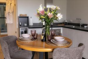 a wooden table with a vase of flowers on it at La Tereza Apartments in Ķesterciems