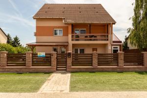 a house with a wooden fence in front of it at Tengercsillag Vendégház in Alsóörs