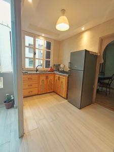 Una cocina con refrigerador de acero inoxidable y gabinetes de madera. en White House, en Mirleft