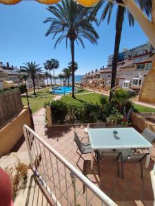 a balcony with a table and chairs and palm trees at Casa primera línea vistas al mar con Parking in La Venteta