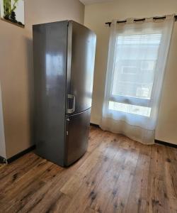 a stainless steel refrigerator in a room with a window at Appartement blue sky unique et élégante in Lomé