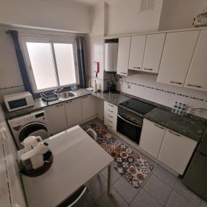 a small kitchen with white cabinets and a table at Ina's Garden in Santa Cruz in Santa Cruz