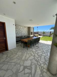 a patio with a wooden table and chairs at Casa Ventus - Arpoeiras Beach - Pé na Areia in Acaraú