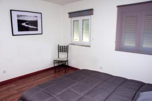 a bedroom with a bed and a window and a chair at Cantinho do Ze Padeiro in Tabuaço
