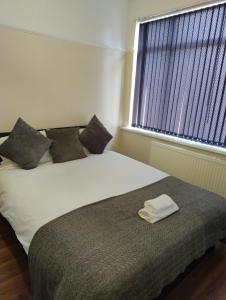 Un dormitorio con una cama con dos almohadas y una ventana. en Mancunian Pride Villa, en Mánchester