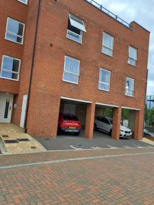 a red car parked in a parking lot in front of a brick building at Ebbsfleet International Homestay in Swanscombe