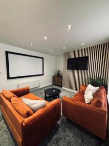 a living room with two orange couches and a flat screen tv at apartment block- great for contractors in Hull +17 photos