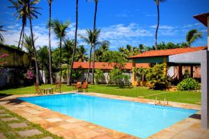 a swimming pool in front of a house with palm trees at Casa Mandacaru Cumbuco in Cumbuco