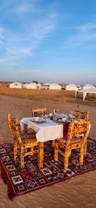 a wooden table and chairs on the beach at Tranquil gem luxury camp in Merzouga