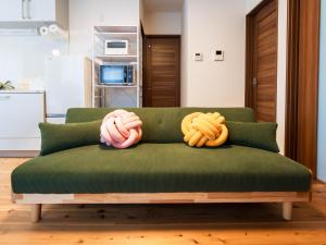 a green couch with two pillows on top of it at 88kawaramachi 一軒家 in Takamatsu