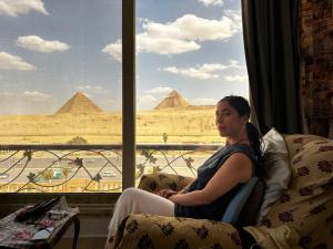 una mujer sentada en una silla mirando por una ventana a las pirámides en Nader home, en Giza