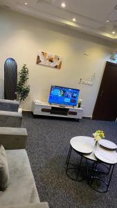 a living room with a tv and two tables at شقة بصالة وغرفة نوم حديثة جازان in Jazan