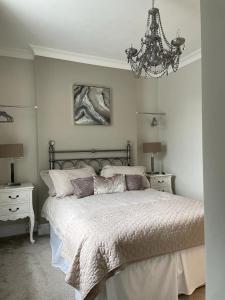 a bedroom with a large bed and a chandelier at Upper Rockdale High St Abersoch in Abersoch +12 photos