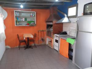 a kitchen with orange walls and a table and a refrigerator at Posada del Valle in San Agustín de Valle Fértil