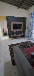 un salon avec une télévision à écran plat sur un mur dans l'établissement Cantinho do sossego, à Cabo Frio