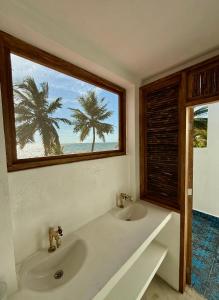 a bathroom with a sink and a window with palm trees at Casa Manglar in Tolú +60 photos