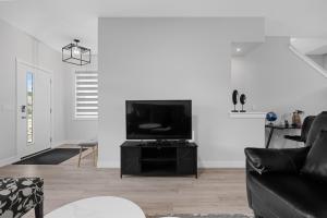 Una sala de estar con un sofá negro y un televisor. en Cozy and inviting 3BR Entire Home in Calgary for holidays and gatherings free parking for two cars, en Calgary