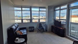 a living room with a couch and a tv and windows at 2 Bed Apartment-Panoramic Views in Napier